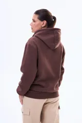 Buzo tipo canguro de felpa color marrón, con capucha ajustable mediante cordones y bolsillo frontal tipo canguro.