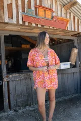 Camisa de corte holgado con estampado floral en tonos naranja y rosa, cuello clásico, manga corta y cierre frontal con botones de madera.