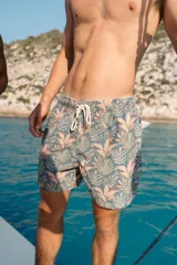 Short de baño con estampado botánico de hojas en tonos verdes y salmón sobre fondo gris azulado. Cuenta con cintura elástica con cordón ajustable, dos bolsillos laterales y un bolsillo trasero.