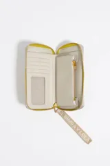 Billetera rígida de color negro con cierre de cremallera perimetral. Presenta el logo metálico de Bimba y Lola en color dorado en el frente y un tirador de cordón trenzado en tonos marrón y amarillo. El interior cuenta con compartimentos para tarjetas y un monedero con cierre.