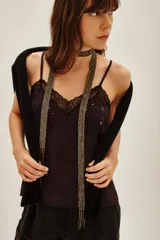 Top lencero de satén color negro con escote en V, decorado con encaje floral y pequeñas aplicaciones brillantes. Presenta breteles finos ajustables.