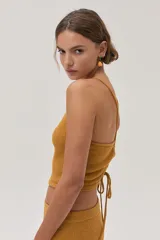 Top halter tejido texturizado en tono mostaza con tiras finas que se atan en la espalda.