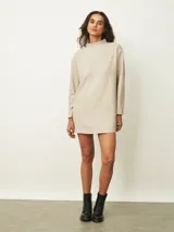 Vestido corto de color beige con cuello alto y mangas largas, de corte recto y holgado.