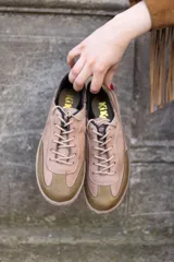 Sneaker de cuero en tonos taupe y verde oliva, con diseño de paneles, cordones al tono y suela de goma plana.