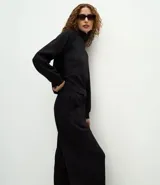 Pantalón de corte recto con cintura estructurada y lazo ajustable. Presenta un diseño básico y versátil con aberturas laterales en el ruedo.