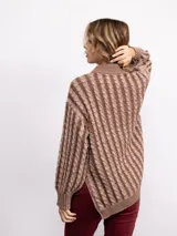 Sweater de punto con diseño de trenzas verticales, cuello alto y silueta oversize. Presenta un patrón bicolor en tonos azul y azul oscuro, con mangas largas y terminaciones en tejido acanalado.