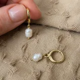 Aros abridores tipo argolla dorados con un dije colgante de perla de río barroca.