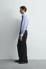 Camisa de corte regular fit confeccionada en tejido ligero de algodón, con diseño de rayas verticales azules y blancas. Presenta cuello abotonado y puños en color blanco a contraste, con cierre frontal de botones.