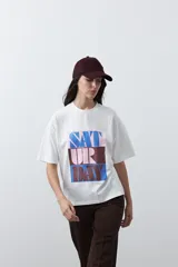 Remera de manga corta con corte boxy fit, color blanco, con estampa frontal geométrica en tonos azul, rosado y marrón.