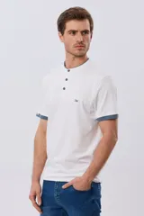 Remera blanca de manga corta con cuello mao y cierre frontal parcial con tres botones. Presenta detalles en color azul en el cuello y en los bordes de las mangas, además de un pequeño logo bordado en el pecho.