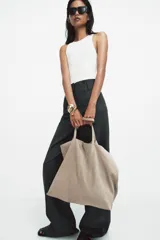 Bolso tipo maxi shopper confeccionado en serraje, con diseño minimalista y doble asa de hombro. Cuenta con un compartimento principal amplio y un bolsillo interior con cierre.