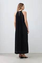 Vestido largo negro plisado con cuello halter y cinturón plateado.