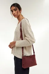 Bandolera pequeña de cuero gamuzado color bordó, con correa larga regulable y cierre superior.