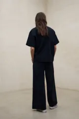 Camisa negra de manga corta con tejido de textura seersucker, corte oversize, cuello camisero y cierre frontal con botones.