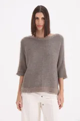 Sweater de tejido de punto con terminaciones de flecos en el cuello, mangas y ruedo. Presenta un corte holgado, mangas tres cuartos y una costura central vertical.