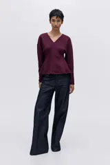 Top de tejido suave con efecto neopreno, escote en V y diseño de cintura entallada. Presenta hombros caídos, mangas largas y puños ajustados.