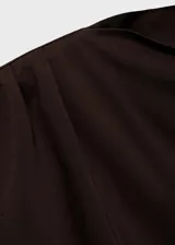 Camiseta color beige de tejido fluido con cuello asimétrico, diseño recto y detalles fruncidos.