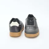 Zapatillas urbanas bajas de cuero sintético negro con puntera gris y suela marrón.