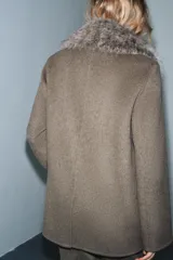 Chaqueta de corte recto confeccionada en mezcla de lana, color marrón topo. Presenta un cuello de solapa amplio con aplicación de pelo sintético desmontable, cierre frontal cruzado con botones y bolsillos laterales con solapa.