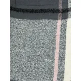 Bufanda rectangular de tejido grueso con diseño de cuadros en tonos azul, naranja, gris y beige, terminada con flecos en los extremos.