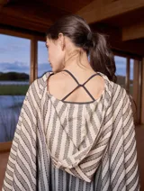 Poncho con capucha a rayas horizontales en tonos gris y blanco.