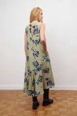 Vestido midi color beige con estampado de hojas en tonos violeta, verde y negro. Diseño sin mangas, con escote redondo y falda acampanada.