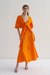 Falda midi naranja de lino con corte recto, tiro medio y abertura frontal con botones.