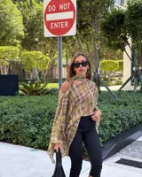 Blusa transparente de gasa con estampado a cuadros en tonos marrón y amarillo, corte asimétrico con hombros caídos y bufanda tipo choker integrada.
