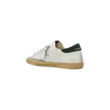 Championes Golden Goose modelo Super Star, de color blanco con acabado envejecido, suela de goma marrón y detalles en negro y dorado.