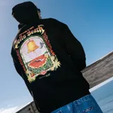 Canguro negro con capucha y bolsillo tipo canguro, confeccionado con felpa de algodón. Presenta un gran estampado gráfico en la espalda con la inscripción 'Bells Beach Australia' y un diseño alusivo al evento de surf, con llamas en los laterales.