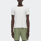 Remera deportiva New Balance Athletics, color blanco hueso, con cuello redondo y manga corta. Presenta un pequeño logo NB reflectante en el pecho.