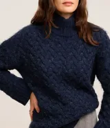 Suéter azul marino de punto trenzado con cuello alto y mangas largas.