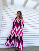 Vestido camisero largo con diseño de estampado chevron en colores fucsia, beige y negro. Presenta cuello camisero, cierre frontal con botones y mangas tres cuartos.