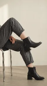 Bota tipo chelsea de cuero negro con paneles elásticos laterales y taco cuadrado de madera de 6 cm.