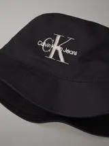 Gorro tipo bucket negro de algodón con ala caída y bordado frontal del logo de Calvin Klein Jeans en hilo plateado.