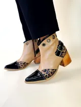 Bota tejana de cuero, combinada en color tostado, animal print de leopardo y puntera en charol negro. Cuenta con taco de madera, detalle de hebilla lateral y ojales metálicos en la parte superior.