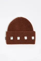 Gorro tipo beanie de punto acanalado color marrón, con vuelta y aplicación de cuatro cristales rectangulares transparentes en la parte frontal.