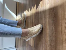 Zapatillas de cuero negro con diseño entretejido y suela blanca.