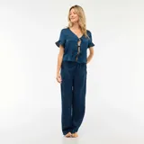 Conjunto de pijama compuesto por una blusa de manga corta con volados y cierre frontal mediante lazos, y un pantalón de corte recto con cintura elástica, confeccionado en tela con textura tipo crepé.