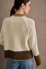 Cardigan de punto con diseño color block en tonos bordó, verde oliva y beige. Presenta cuello redondo con detalle en celeste, cierre frontal con botones y puños acampanados en color beige.