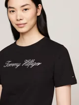 Remera negra de algodón orgánico con cuello redondo y mangas cortas. Presenta el logo script de Tommy Hilfiger bordado en blanco en el pecho y el logo de Tommy Hilfiger bordado en la manga.
