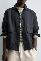 Sobrecamisa relaxed fit confeccionada en tejido de lino de color negro, con cuello solapa, manga larga con puño abotonado, bolsillos de plastrón en la cadera y cierre frontal de botones.