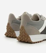 Championes estilo jogging con diseño de paneles en tonos gris, blanco y negro. Presentan cierre por cordones, suela de goma con relieve que se extiende hacia el talón y acabado en poliuretano.