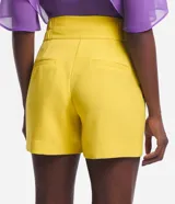 Bermuda roja de poliéster con cintura elástica, bolsillos laterales y cierre con cremallera y botones.