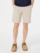 Bermuda de gabardina color beige con cintura elástica y cordón ajustable. Presenta bolsillos laterales y ruedo con dobladillo.