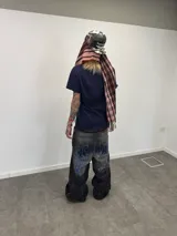 Jean de corte amplio en color negro con efecto acid wash. Presenta cierres laterales metálicos que permiten ajustar la silueta entre corte recto, oxford o baggy. Incluye una estampa gráfica de gran tamaño en la parte trasera con detalles bordados, bolsillos amplios y una etiqueta de cuero legítimo en la cintura.