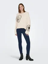 Sweater tejido de color beige con cuello redondo, mangas largas y detalles de bordado floral en negro.