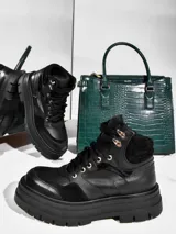 Borcegos de cuero vacuno color negro, con suela track de plataforma alta, cordones frontales con ganchos metálicos y combinación de texturas en cuero liso y gamuza.