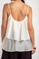 Top de tirantes blancos con diseño fluido y volado superpuesto en el pecho.