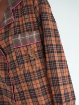 Conjunto de pijama a cuadros con ribetes en color lila, compuesto por camisa de manga larga con botones y pantalón largo.